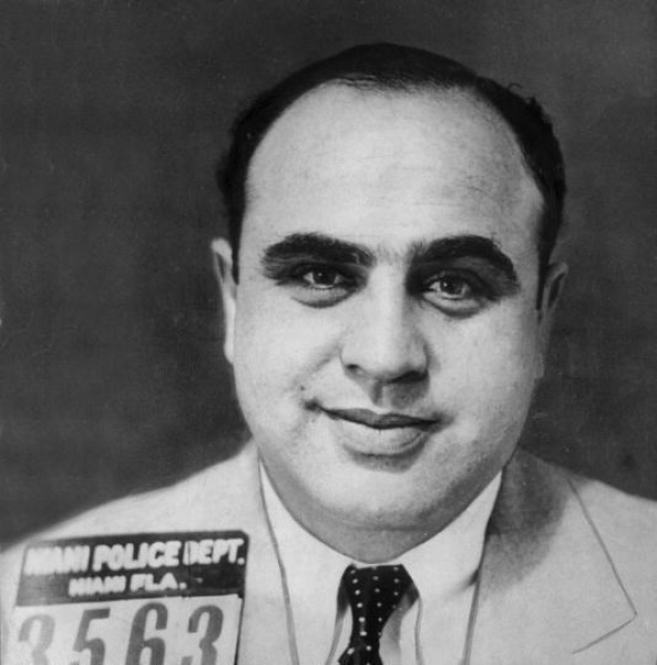 Al Capone在迈阿密被捕时的存档照片，这次逮捕当日即被释放。他所有被捕的存档照上都有他的招牌微笑。他的名言是：微笑的人办事方便，而微笑的人带把枪办事则更方便。
